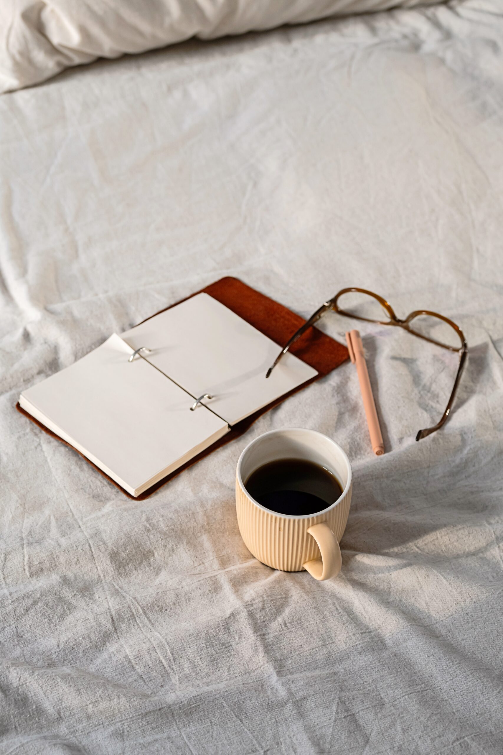 book glasses and cup of coffee on bed